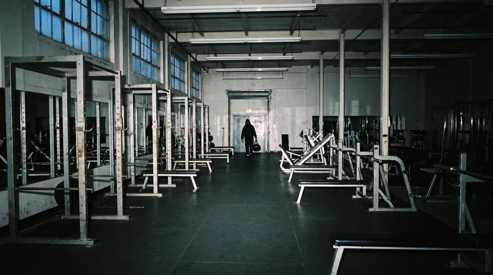 An empty gym at 6am, one person walking in