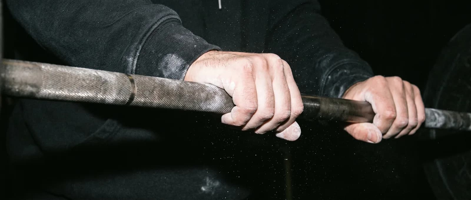 Chalked hands gripping a barbell