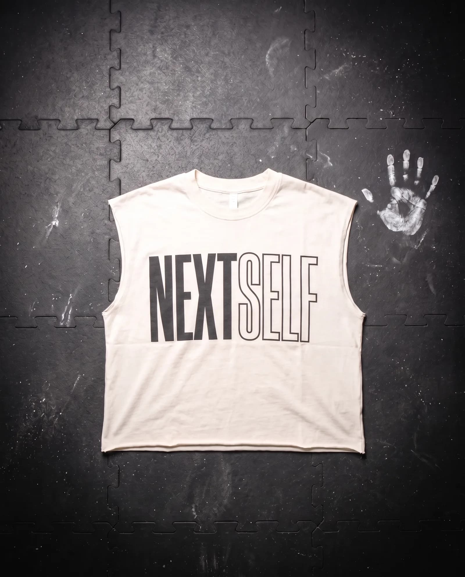 Muscle Tee in Chalk, laid flat on a gym floor