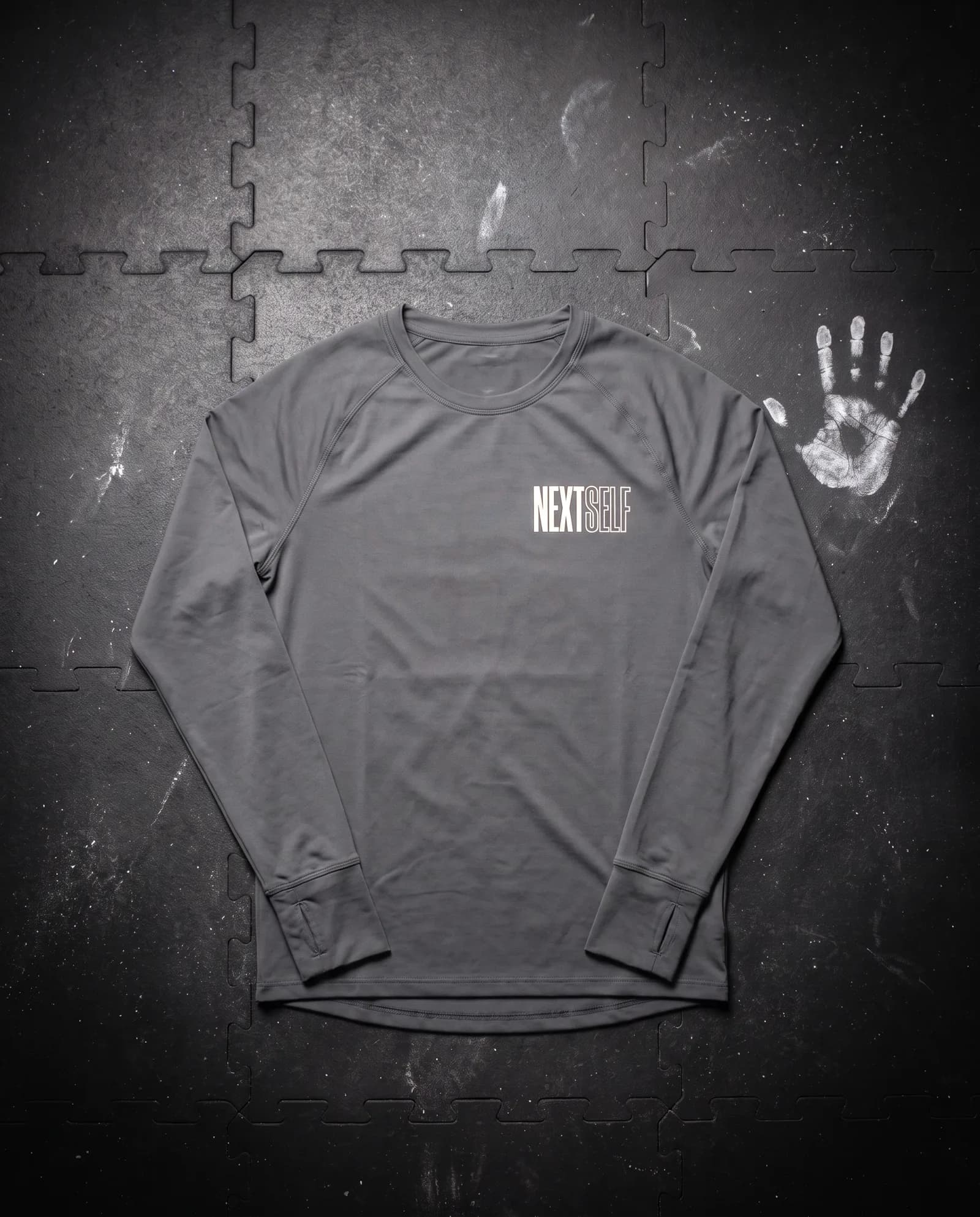 Pace Long Sleeve in Graphite, laid flat on a gym floor