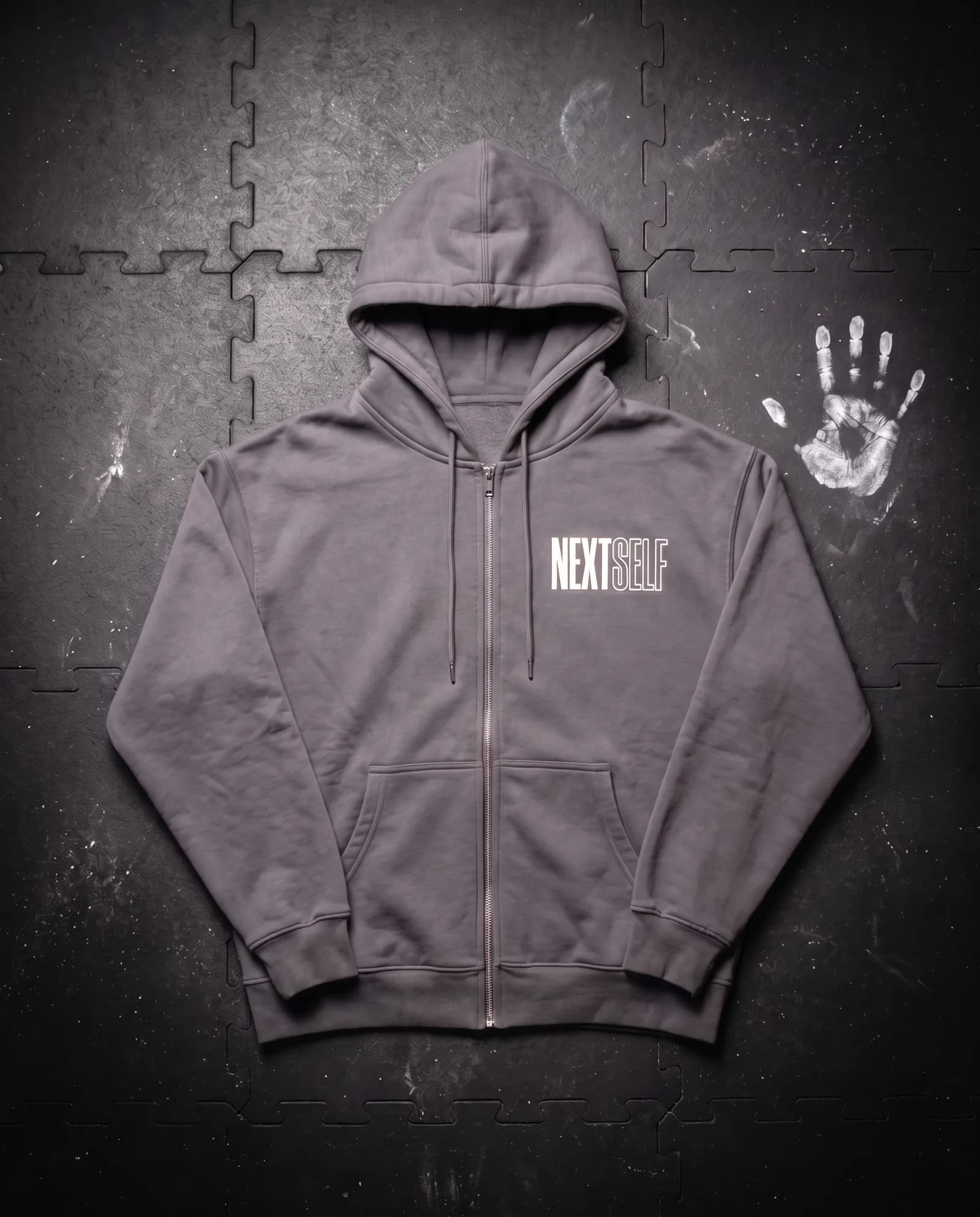 Rest Day Zip Hoodie in Graphite, laid flat on a gym floor